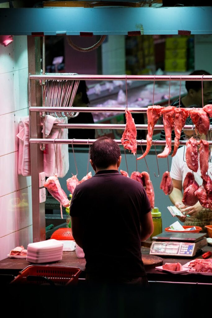 Butcher working in a vibrant Hong Kong market stall preparing fresh cuts of meat.